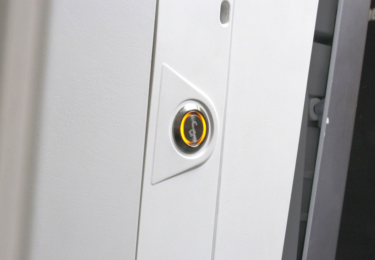 A Door Unlock button with light pipe on a Bayer in Radiology device.