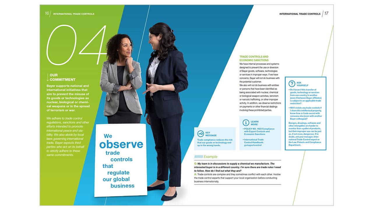 Two people in business attire stand discussing in front of a colorful informational display about trade controls and regulations.