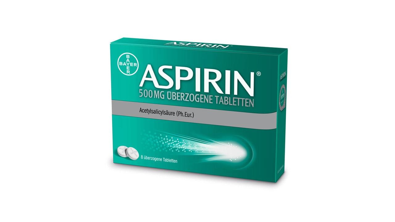 A green box of Bayer Aspirin, labeled "500 mg überzogene Tabletten," with an image of two pills.