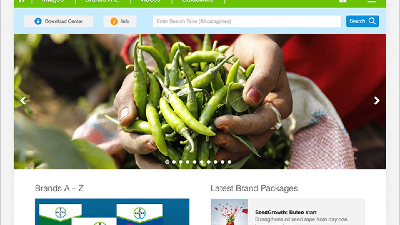 Hands holding green peppers above a website layout for Crop Science ImageBank displaying various image categories and brand packages.