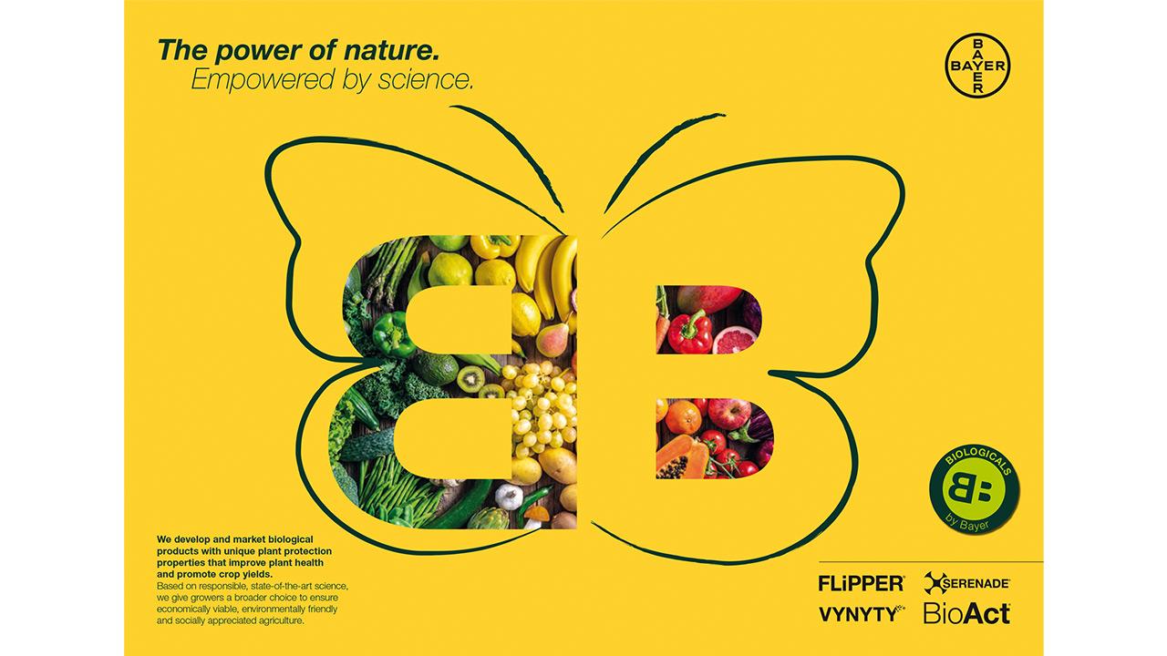 Yellow poster with a butterfly shape containing fruits and vegetables. Text: "The power of nature. Empowered by science." Bayer logo with product names: Flipper, Vynyty, Serenade, BioAct.