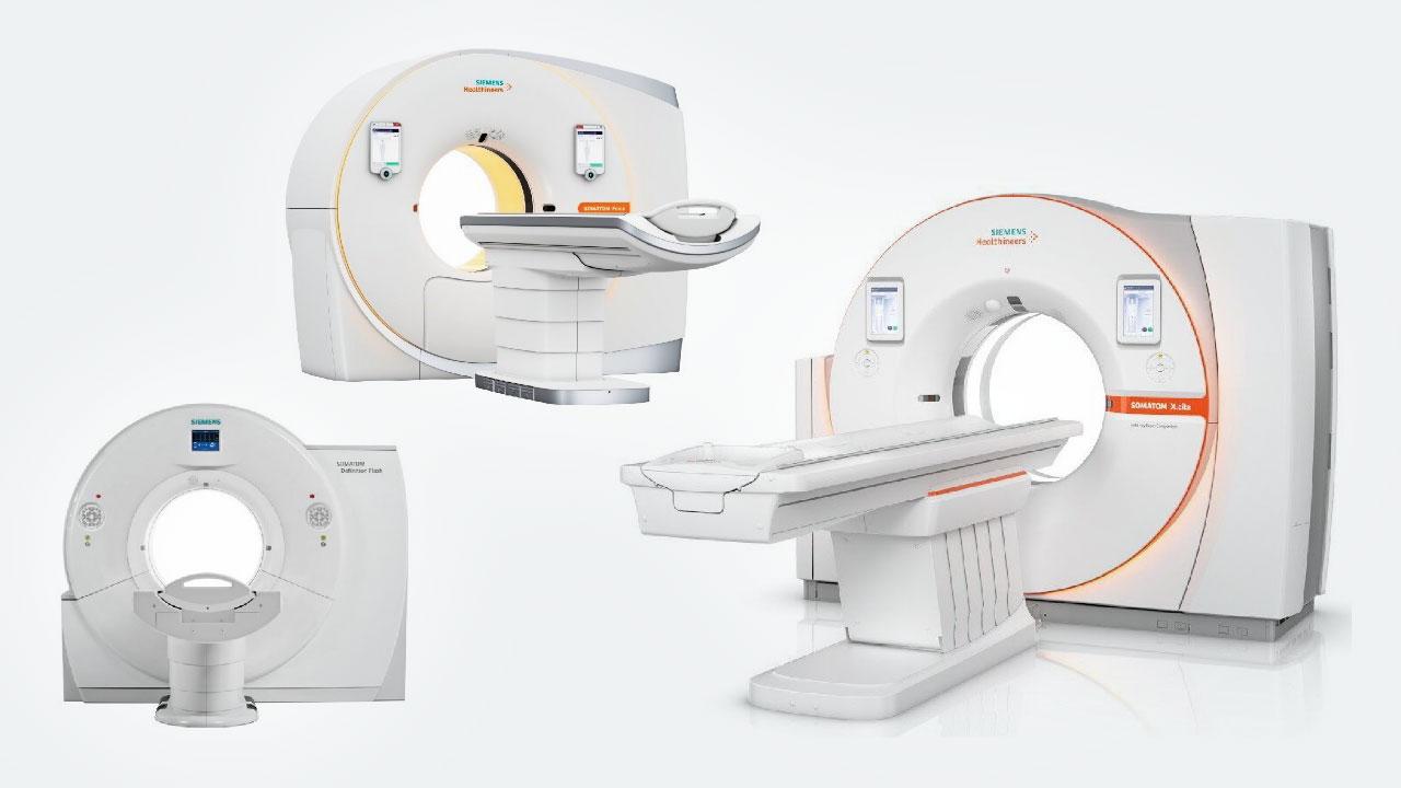 CT scan machines with circular openings and flat patient tables, arranged in a minimalist clinical setting.