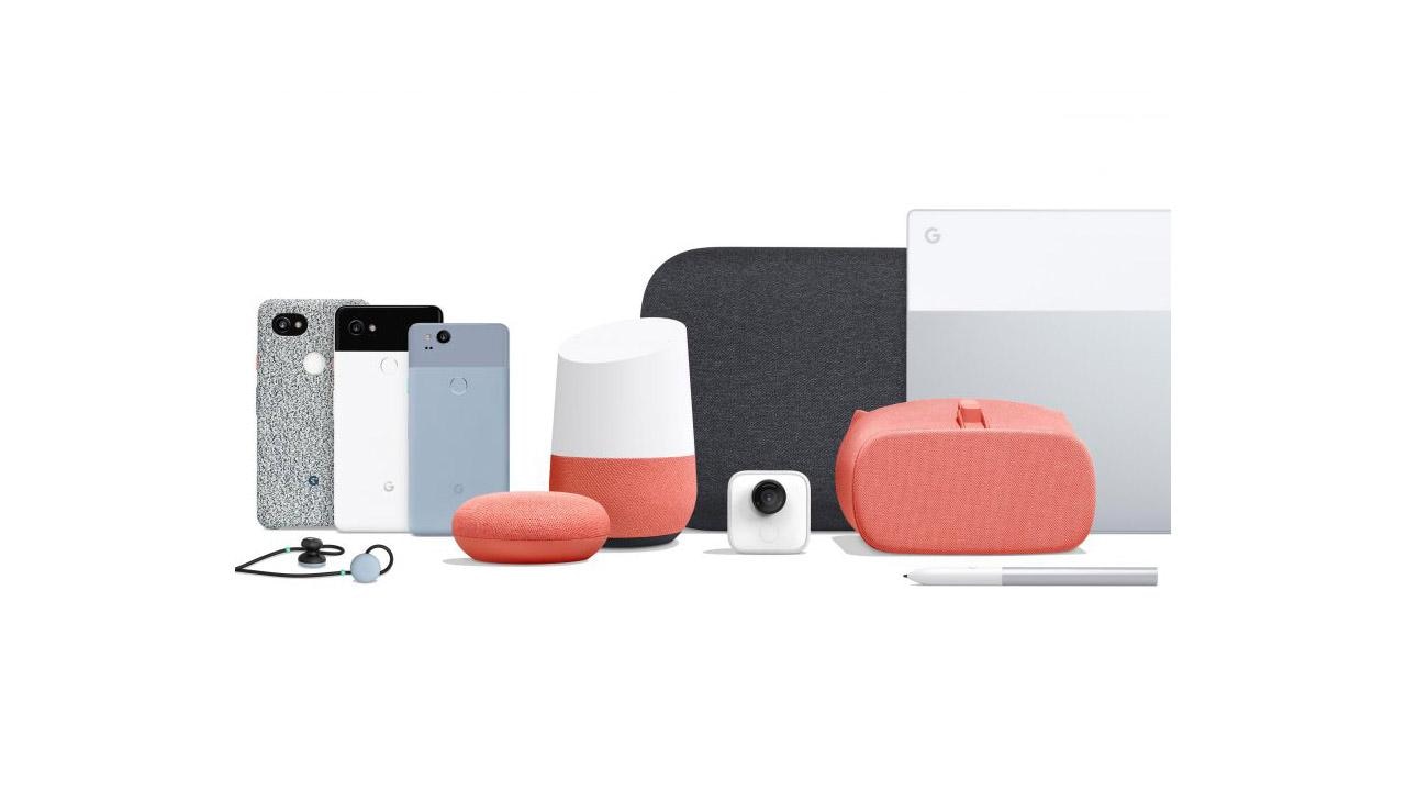 Assortment of Google devices including smartphones, a smart speaker, earbuds, a small camera, VR headset, smart home assistant, and a laptop.