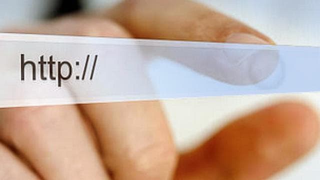 A person's finger hovers over a computer monitor displaying "http://" in the address bar.