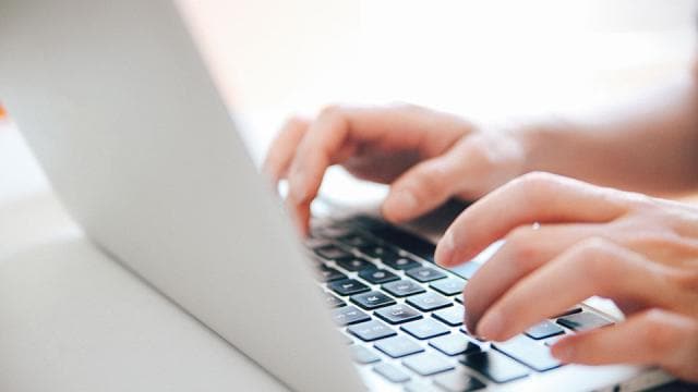 Hands typing on a laptop keyboard.