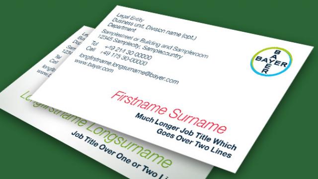 Close-up of two Bayer business cards with sample text, featuring names, job titles, contact details, and the Bayer logo on a green background.