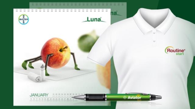 Calendar with a fruit image, a white polo shirt with a red and green logo, and a green pen with "Aviator" text displayed on a green background.