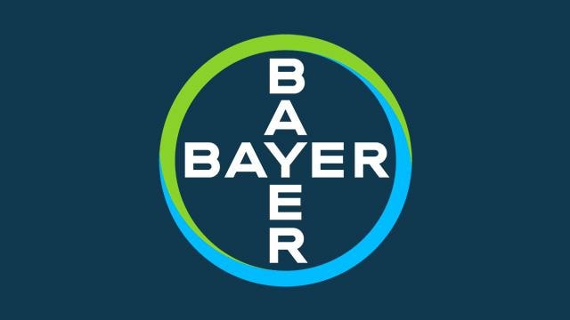 Bayer logo with the word "BAYER" written vertically and horizontally inside a circle with green and blue borders on a dark blue background.