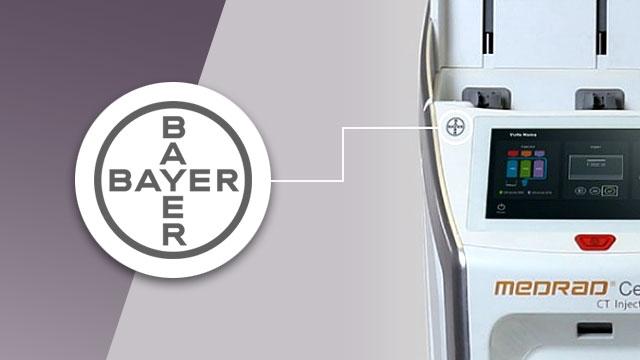 Close-up of a medical device with a Bayer logo on the left and a screen displaying various options on the right.