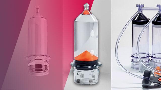Three medical devices: one in a pink hue, a clear container with orange substance in the center, and two clear devices connected with tubing on the right.