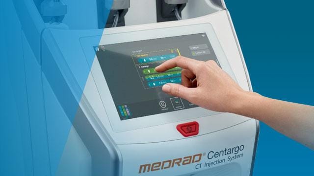 A hand interacts with the touchscreen of a Medrad Centargo CT Injection System.