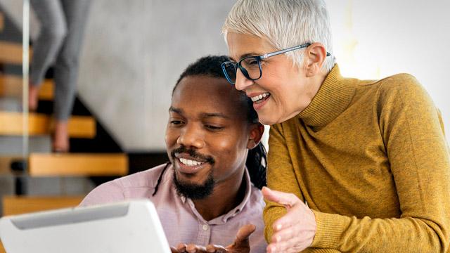 Elderly woman and  young man look at a tablet