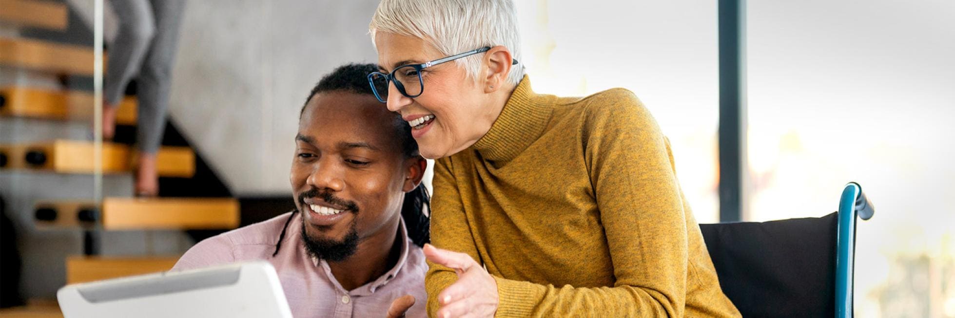 Elderly woman and young man look at a tablet