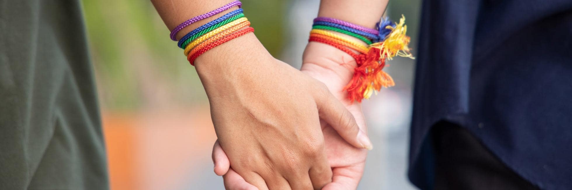 two hands holding hands with rainbow bracelets