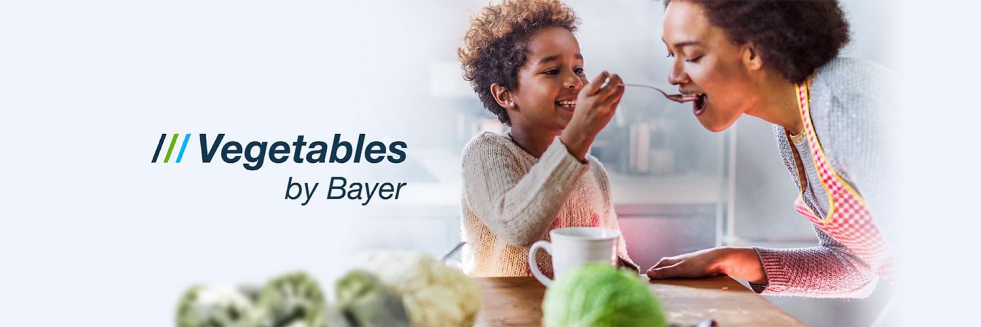 Son feeds mother and text "Vegetables by Bayer"