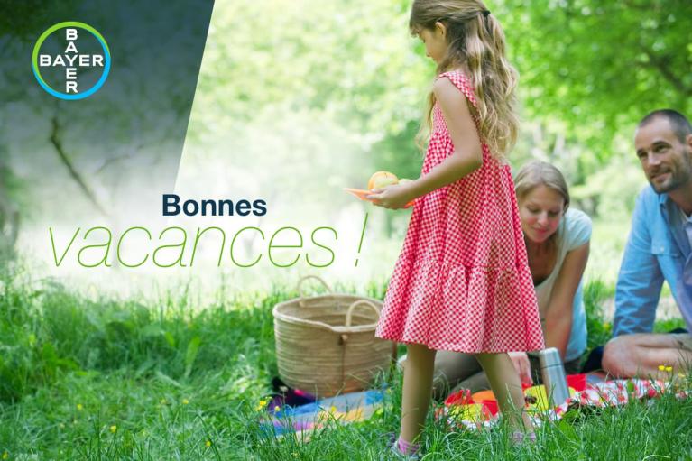 A family enjoys a picnic in a sunny park. A girl in a red dress holds fruit. The text reads "Bonnes vacances!" with the Bayer logo in the top left corner.