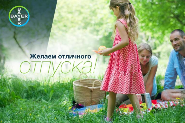 A family enjoys a picnic on the grass with a young girl in a red dress. A basket and blanket are nearby. The text in Russian wishes for a great vacation.
