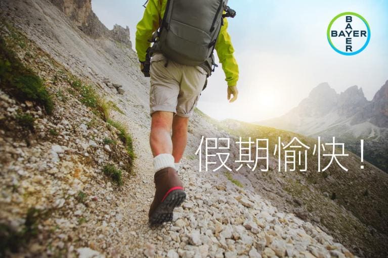 A person hiking up a rocky mountain trail in the sunlight, with a backpack. "假期愉快!" text and a Bayer logo are visible.