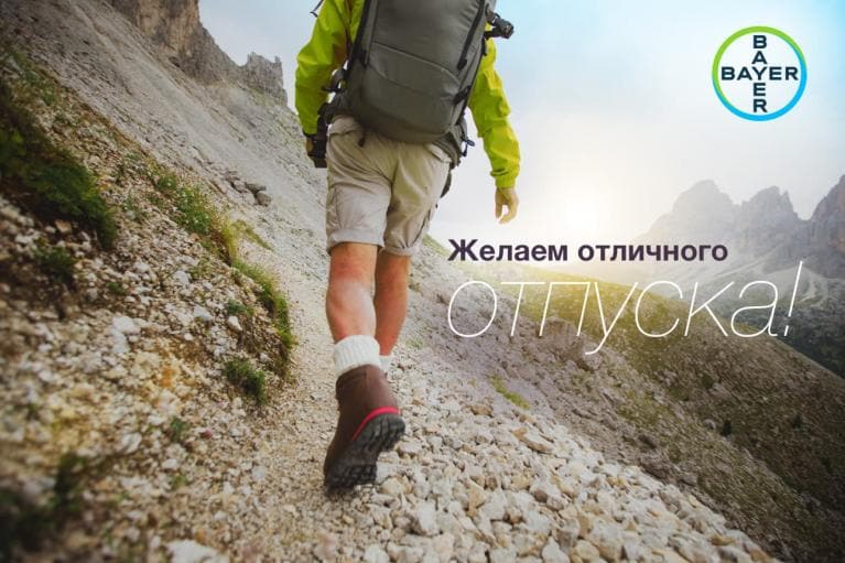 A person hiking uphill on a rocky mountain trail with a backpack. Bayer logo in the corner. Russian text wishing a great vacation.