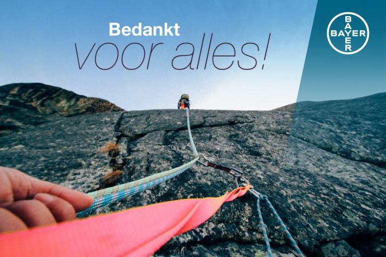 A person climbing a rock face with ropes, shot from below. The text reads "Bedankt voor alles!" with the Bayer logo in the corner.