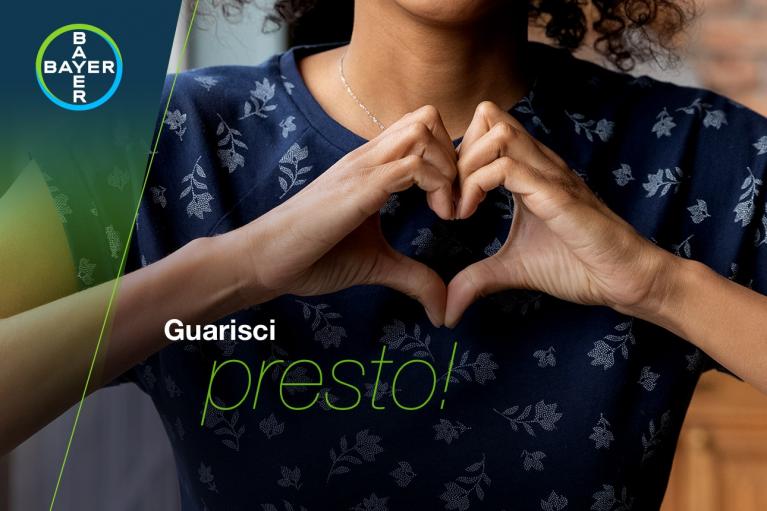 A person forms a heart shape with their hands. The Bayer logo and the text "Guarisci presto!" are visible.
