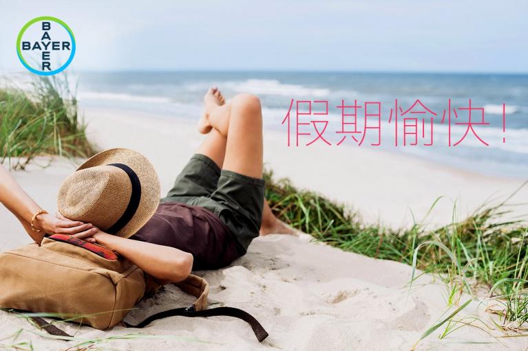 Person relaxing on a sandy beach with grass, wearing a hat, and lying near a backpack. The words "假期愉快" appear on the image.