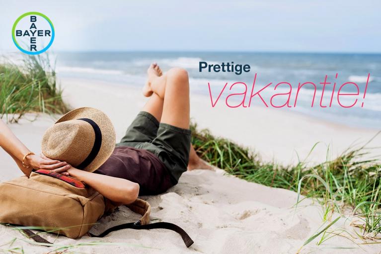 Person relaxing on a beach with a hat covering their face, next to a bag. The text reads, "Prettige vakantie!" with the Bayer logo in the corner.