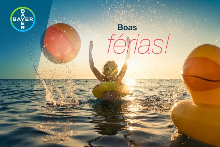 Person in a pool with a beach ball and inflatable duck, arms raised, at sunset. Text reads "Boas férias!" Logo on top left.