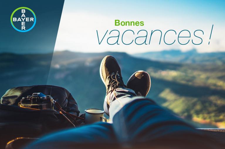 Person relaxing with legs up, overlooking a mountainous landscape, beside a camera and bag. Text reads "Bonnes vacances!" with a Bayer logo in the corner.