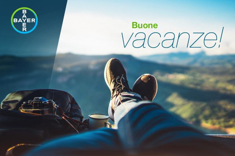 Person relaxing with feet up, overlooking a scenic view. A camera and backpack are beside them. Text reads, "Buone vacanze!" with Bayer logo in the corner.
