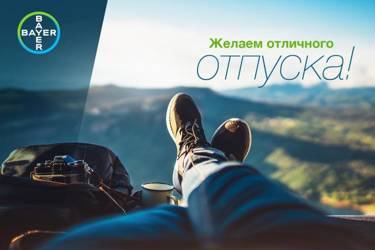 A person relaxes with feet up, overlooking a scenic landscape. A camera bag and a camera are nearby. Text in Russian and Bayer logo are visible.