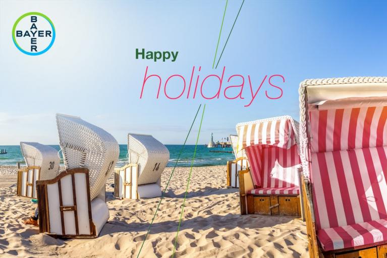 A beach scene with striped beach chairs and a calm sea. Text reads "Happy Holidays" alongside the Bayer logo.