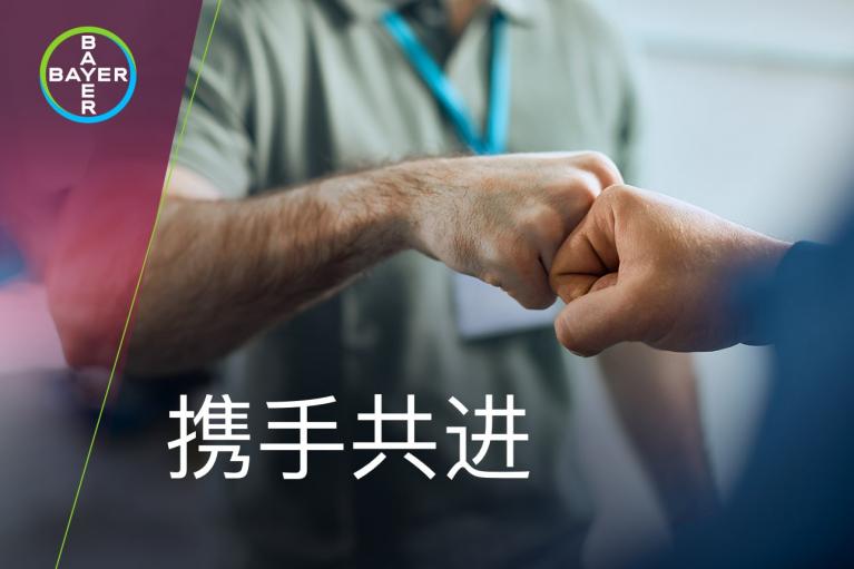 Two individuals giving a fist bump. The Bayer logo is in the top left corner. Chinese text at the bottom reads "携手共进.