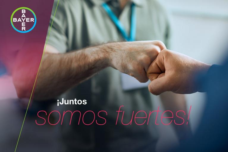 Two people fist bumping with a Bayer logo in the corner. Text reads "¡Juntos somos fuertes!.