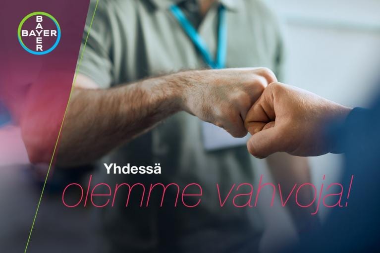 Two people fist bumping in the foreground, with a Bayer logo in the corner. Finnish text reads, "Yhdessä olemme vahvoja!" which means "Together we are strong!.