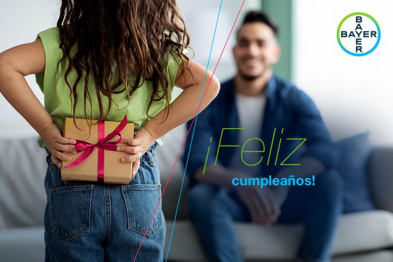 Child with gift behind back facing a seated adult, with the text "¡Feliz cumpleaños!" and Bayer logo.
