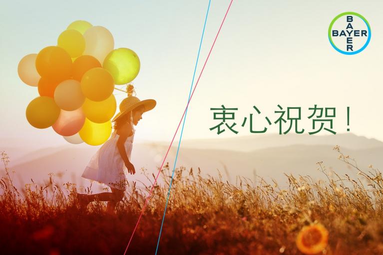 Child in a field holding colorful balloons under a sunny sky, with the Bayer logo and Chinese text on the right.