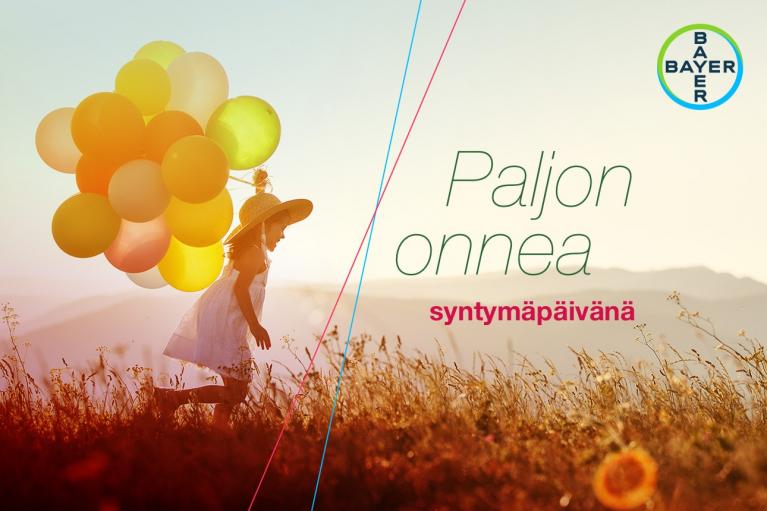 A child with balloons runs through a field. Finnish text "Paljon onnea syntymäpäivänä" and a Bayer logo are present.