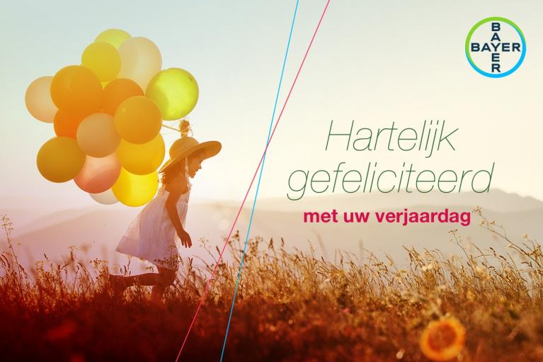Child in a field holding colorful balloons, with the text "Hartelijk gefeliciteerd met uw verjaardag" and a Bayer logo in the top right corner.