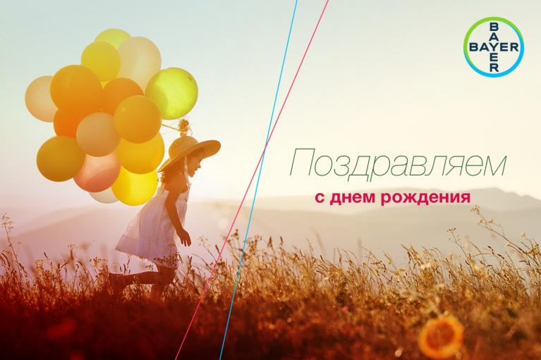 A child with balloons runs in a field at sunset. Birthday greeting and Bayer logo are on the right side.