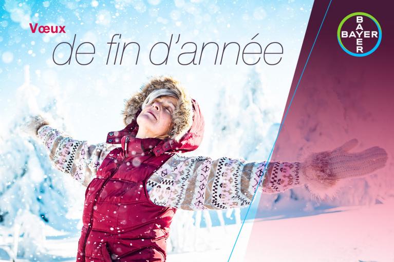 A person in a winter coat stands with open arms in a snowy landscape. Text reads "Vœux de fin d'année" alongside the Bayer logo.