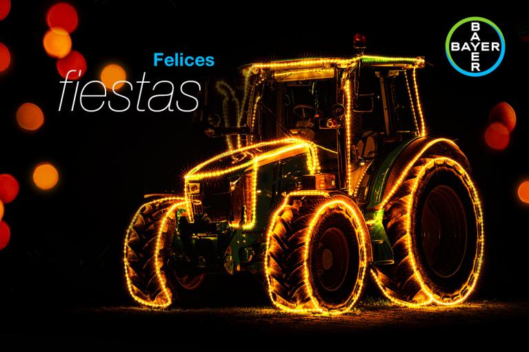 A tractor decorated with festive lights against a dark background with the text "Felices fiestas" and the Bayer logo.
