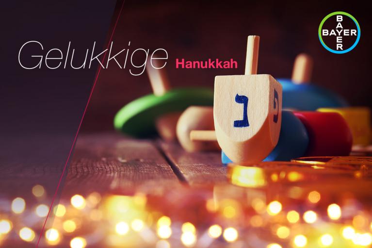 Colorful dreidels and coins on a wooden surface with "Gelukkige Hanukkah" written above.