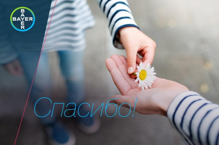 A person hands a daisy to another. The Bayer logo is in the corner, and "Спасибо!" is written in blue text across the image.