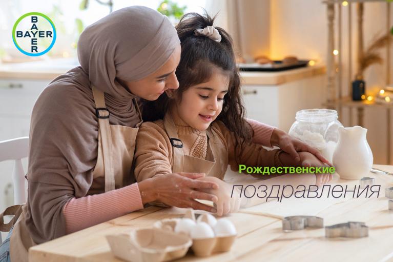 A woman and a child wearing aprons bake together in a kitchen, surrounded by baking utensils and ingredients. The words "Рождественские поздравления" are displayed on the image.