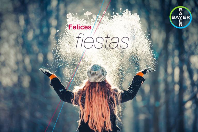 Person wearing a winter coat and hat throws snow in the air. Text reads "Felices fiestas" with a Bayer logo in the corner.