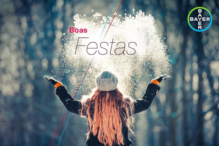 Person in winter clothing throws snow into the air. "Boas Festas" text and Bayer logo are visible.