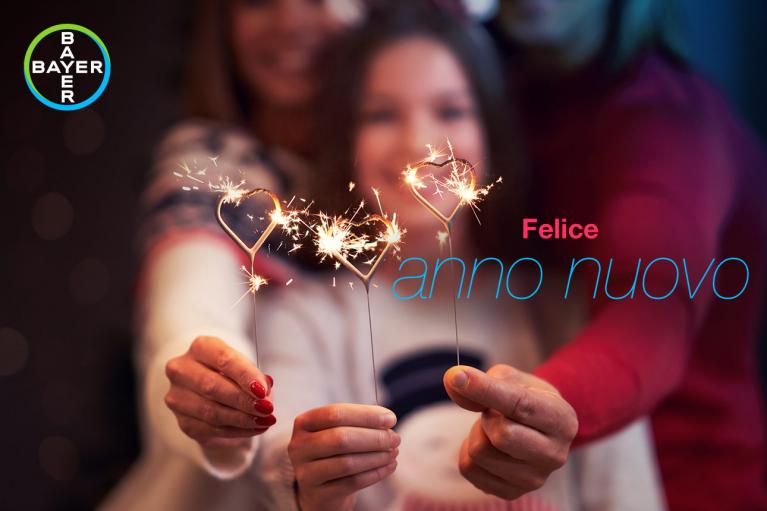 Three people holding sparklers, with a "Felice anno nuovo" message and a Bayer logo in the corner.