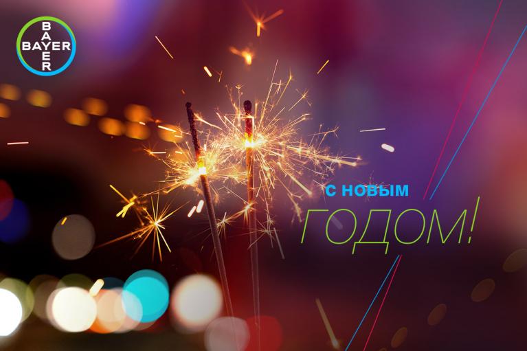 Close-up of sparklers with colorful bokeh lights in the background. Text on the image reads "С Новым Годом!" and "Bayer.