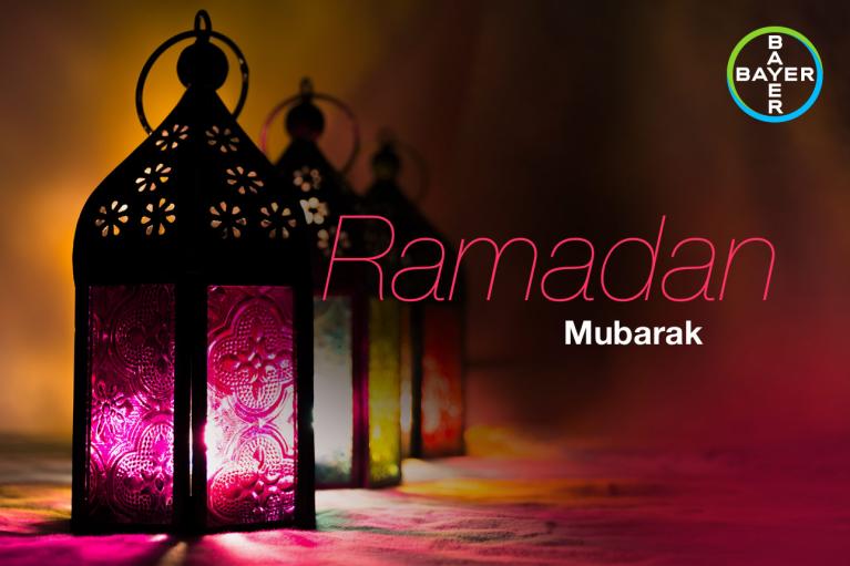 Three ornate lanterns with colorful glass panes are lit, casting a warm glow. The text reads "Ramadan Mubarak" alongside a logo in the top right corner.